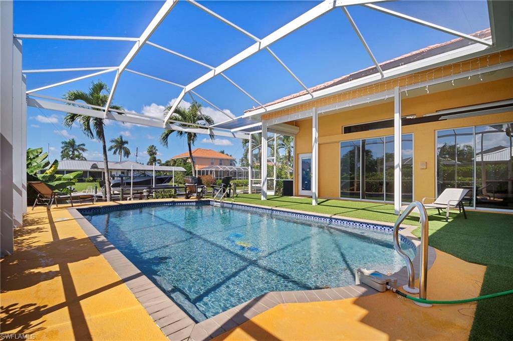 Swimming pool with a sunroom, a lanai, a patio area, and a yard