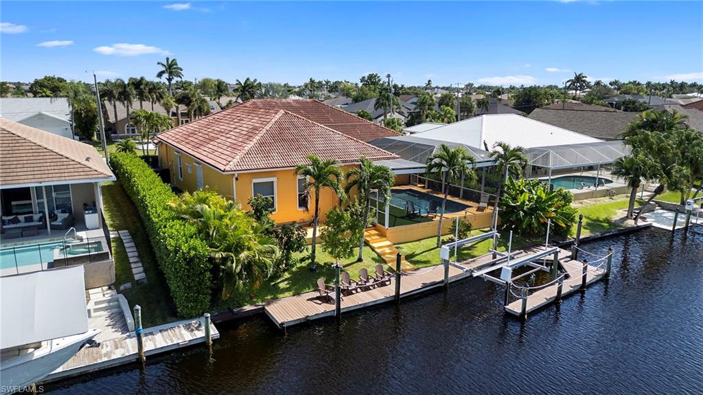 Dock featuring boat lift, a lanai, a water view, an outdoor pool, and a patio