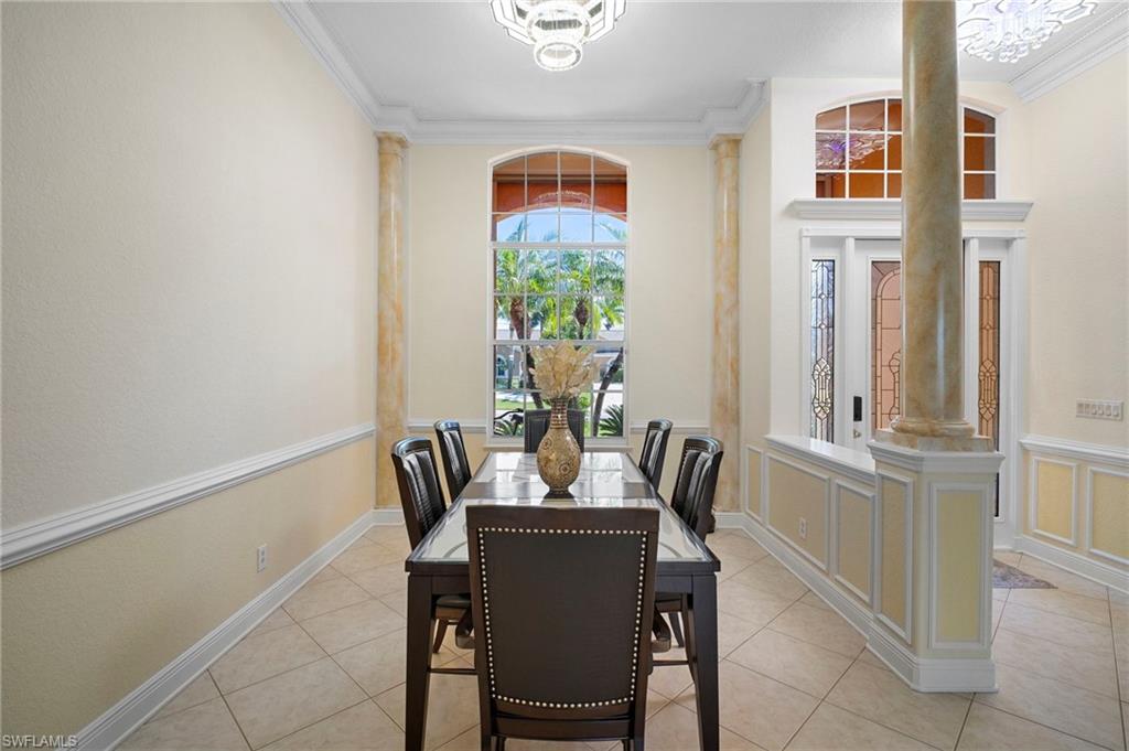 Dining room with crown molding, decorative columns, and tile patterned flooring