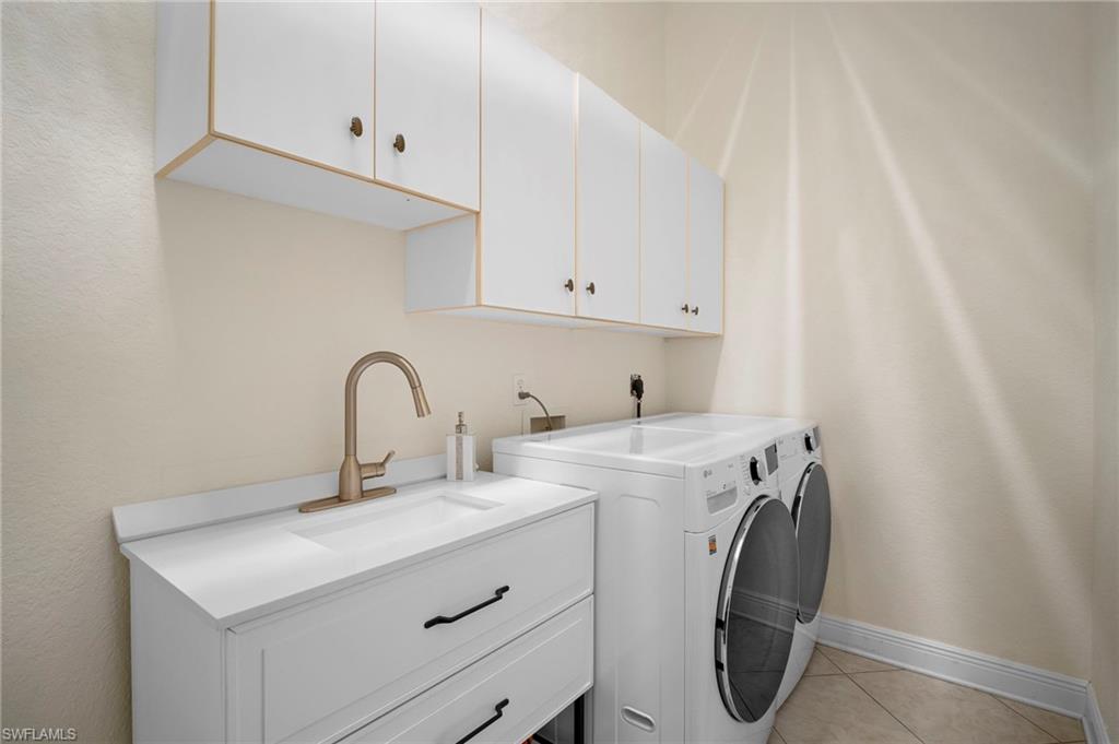 Washroom featuring light tile patterned floors, separate washer and dryer, and cabinet space