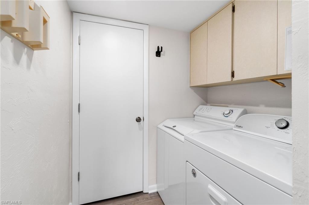 Laundry area featuring light wood-type flooring, separate washer and dryer, and cabinet space