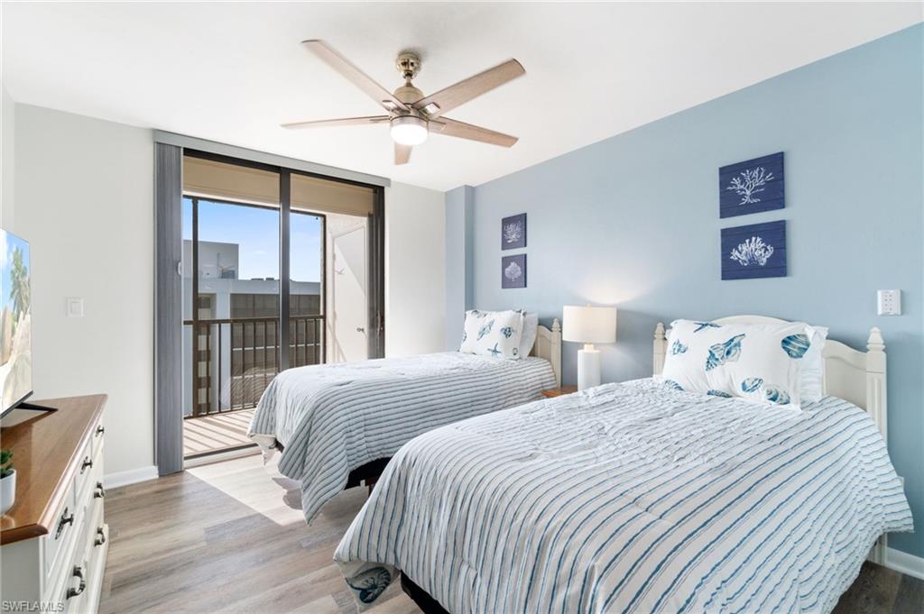 Bedroom featuring wood finished floors, access to outside, ceiling fan, and expansive windows