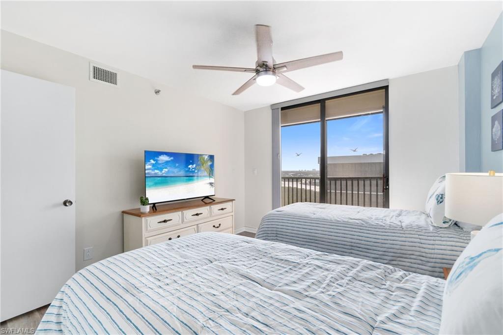 Bedroom with access to exterior, a ceiling fan, floor to ceiling windows, and wood finished floors