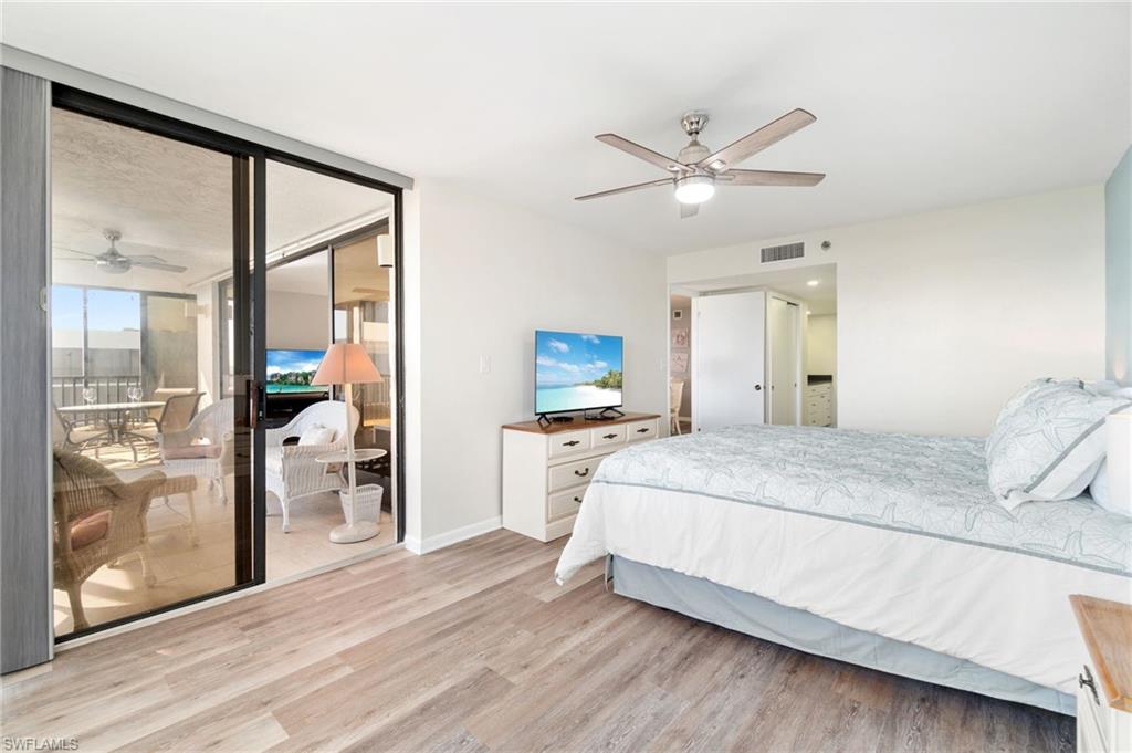 Bedroom with light wood-style floors, ceiling fan, access to exterior, and a wall of windows