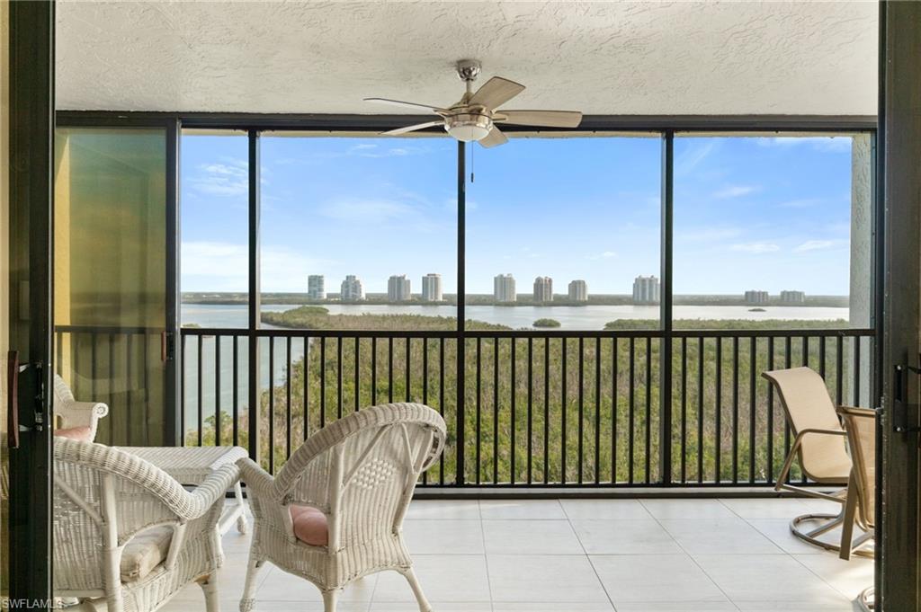 Sunroom featuring tile patterned floors, expansive windows, a water view, a textured ceiling, and plenty of natural light