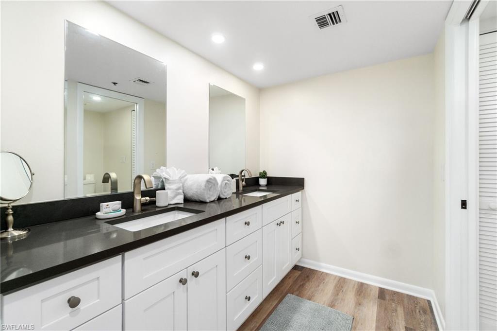 Full bath featuring light wood finished floors, double vanity, recessed lighting, and a closet