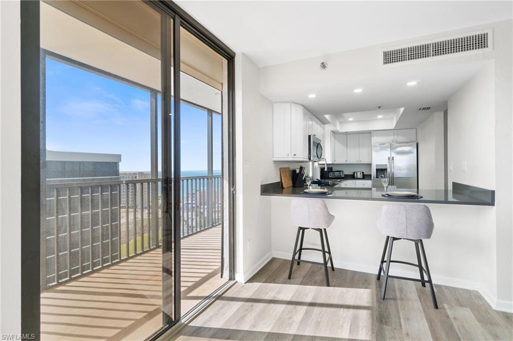 Kitchen featuring light wood finished floors, white cabinetry, appliances with stainless steel finishes, a kitchen bar, and a peninsula
