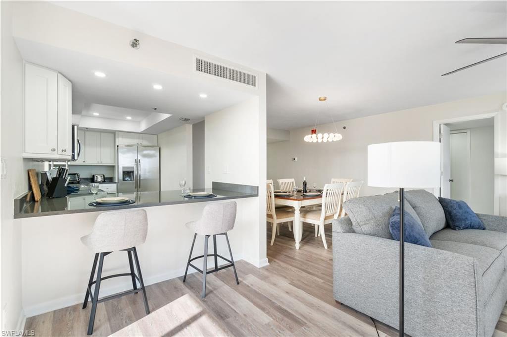 Kitchen with a breakfast bar, light wood finished floors, stainless steel refrigerator with ice dispenser, and recessed lighting