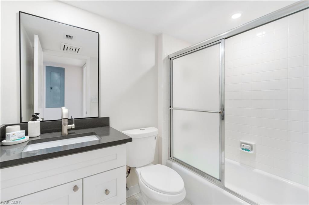 Bathroom featuring combined bath / shower with glass door and vanity