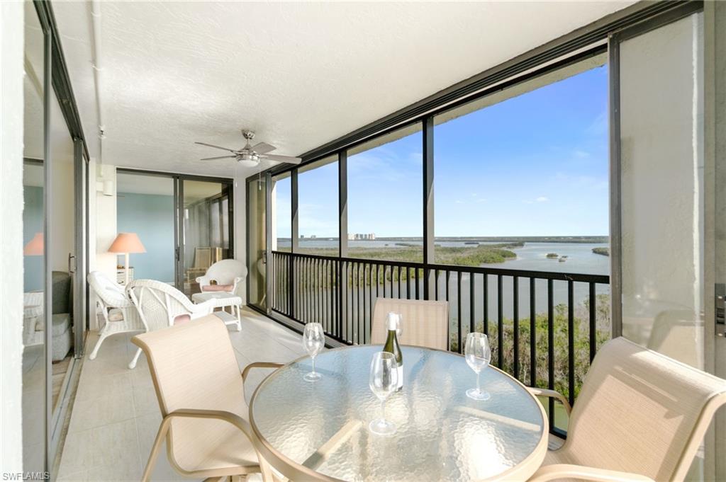 Sunroom featuring a water view, a wall of windows, outdoor dining space, a balcony, and ceiling fan