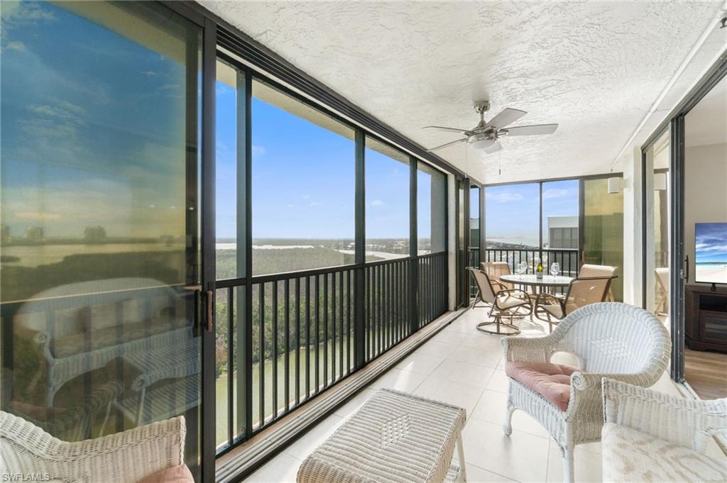 Sunroom / solarium featuring expansive windows, a ceiling fan, a balcony, a textured ceiling, and tile patterned floors