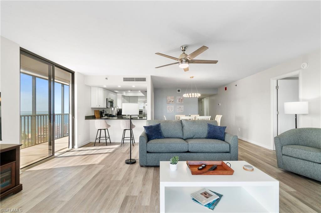 Living room with a water view, light wood-style flooring, ceiling fan, and floor to ceiling windows