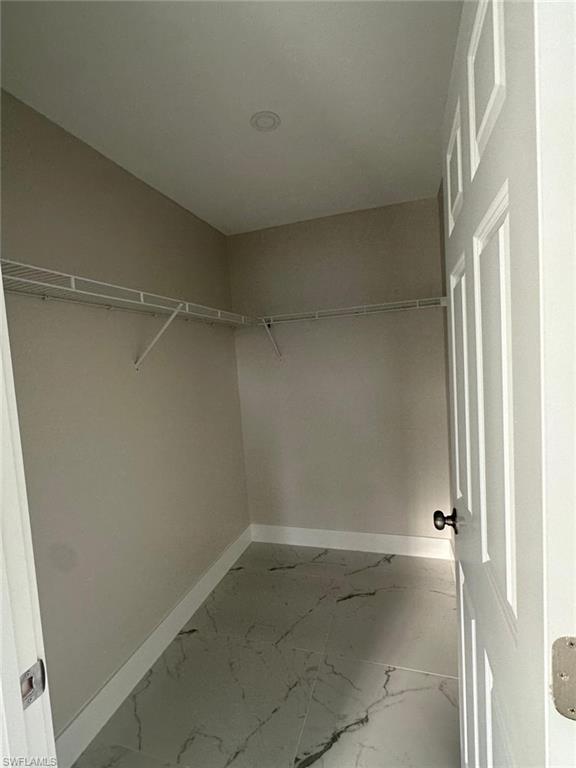 Walk in closet with light marble finish floors