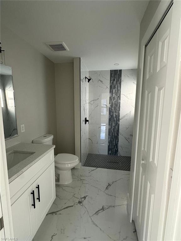 Full bathroom with a marble finish shower, vanity, and light marble finish flooring