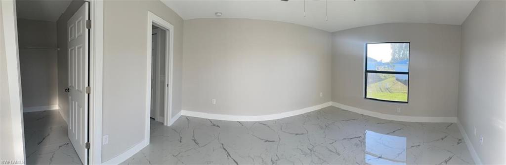 Unfurnished room featuring marble finish floors, ceiling fan, and vaulted ceiling