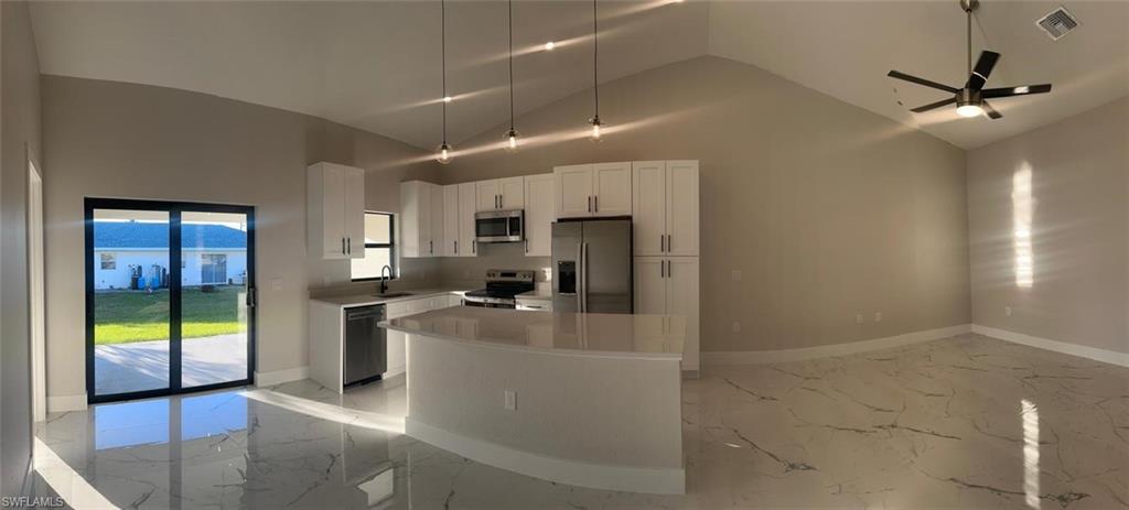 Kitchen featuring light marble finish flooring, white cabinets, appliances with stainless steel finishes, hanging light fixtures, and a ceiling fan