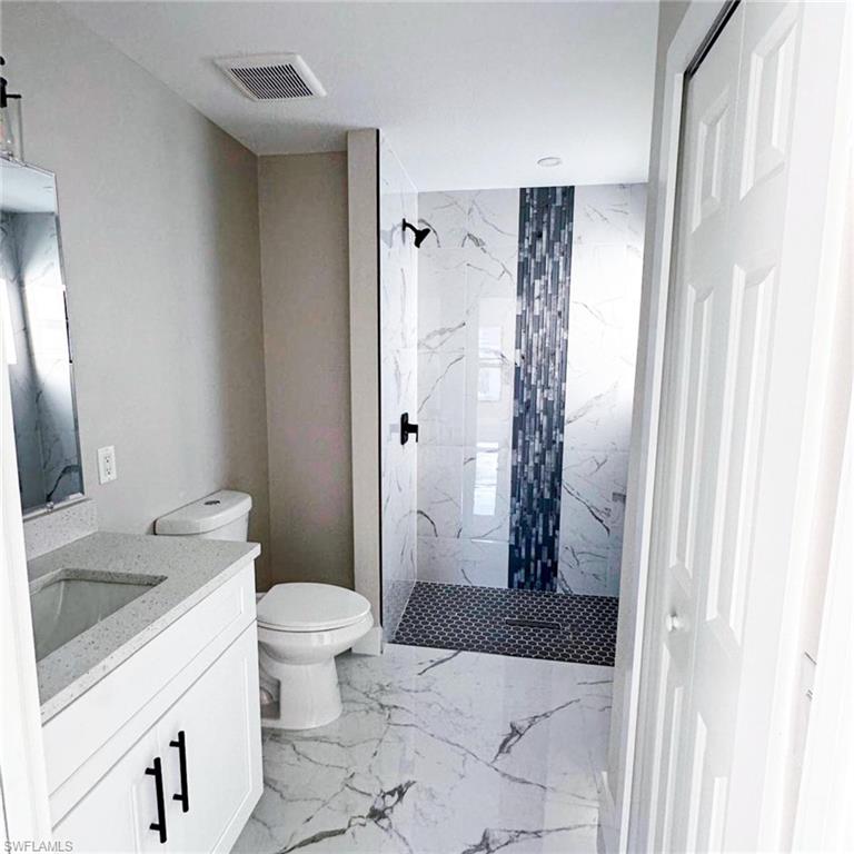 Full bathroom featuring vanity, a marble finish shower, a closet, and light marble finish flooring