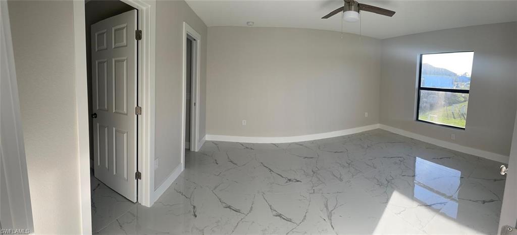 Spare room with light marble finish flooring and a ceiling fan