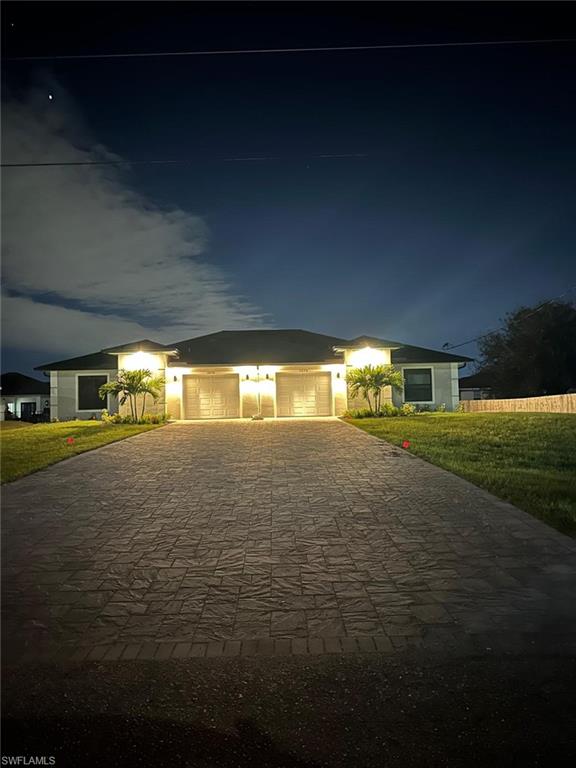 Ranch-style home with decorative driveway, a yard, stucco siding, and an attached garage