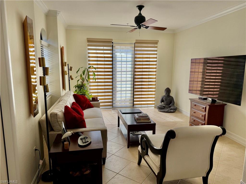 Living area with light tile patterned floors, ornamental molding, and a ceiling fan