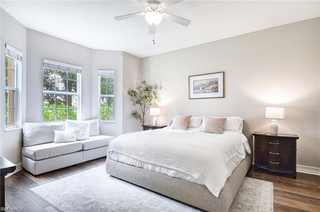 Large primary bedroom en suite with wood grain luxury vinyl floor, lighted ceiling fan