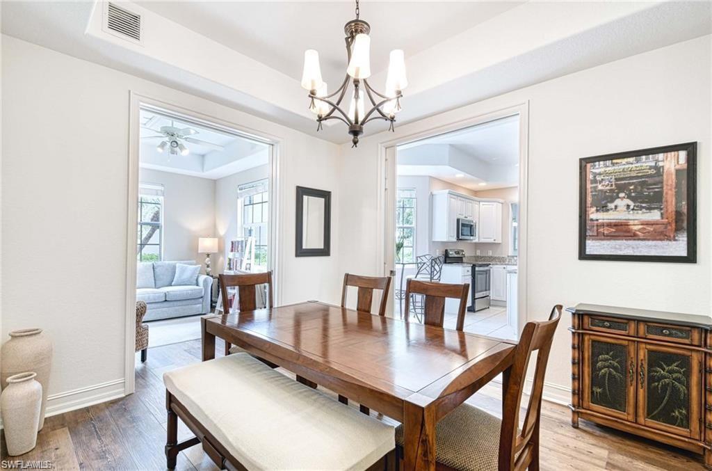 Dining Room with wood grain luxury vinyl and pocket doors to den/office and kitchen. Trey ceiling