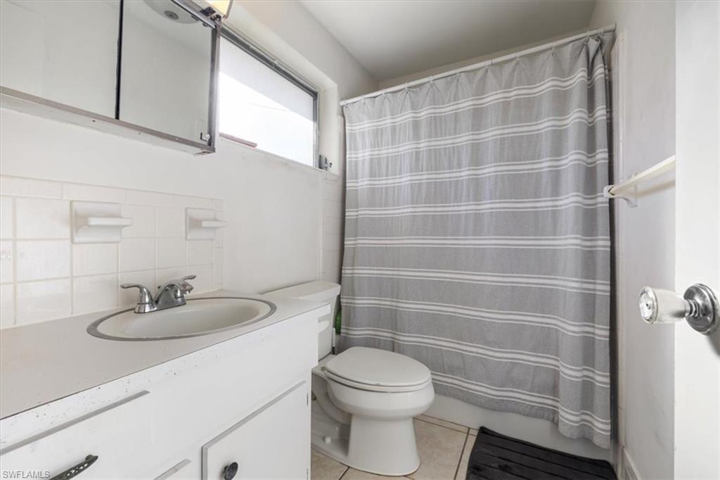 Full bathroom featuring vanity, light tile patterned floors, and backsplash