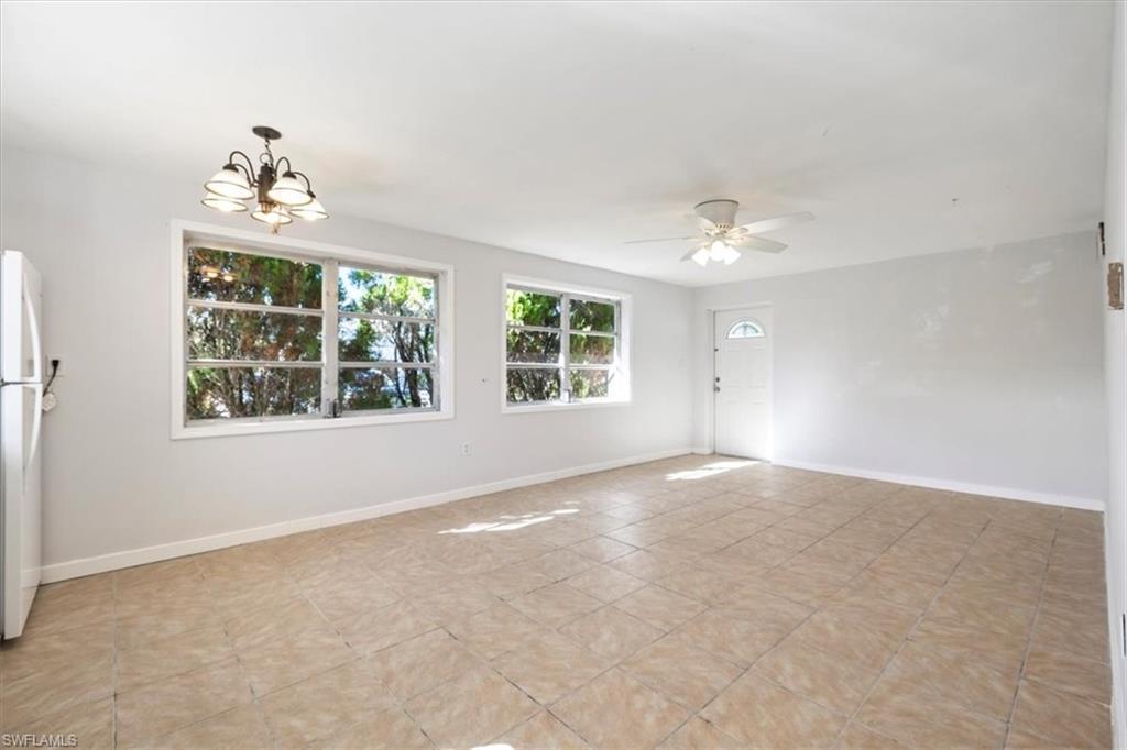 Spare room featuring a chandelier, light tile patterned floors, and a ceiling fan