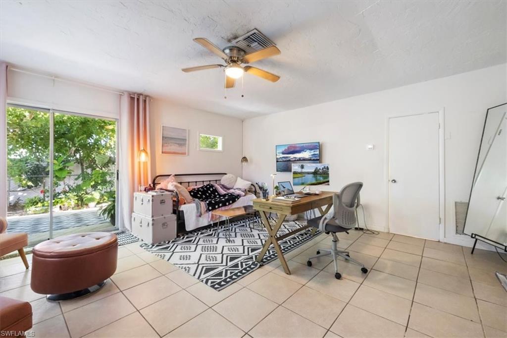 Home office featuring light tile patterned floors, ceiling fan, and a textured ceiling