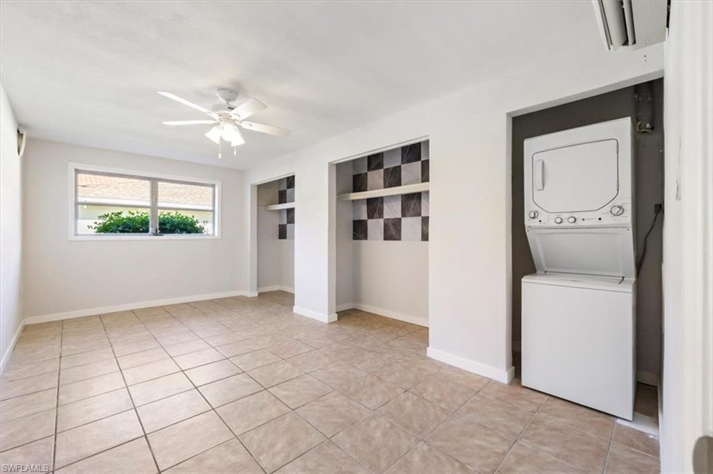 Laundry room with stacked washer / drying machine, light tile patterned floors, and ceiling fan