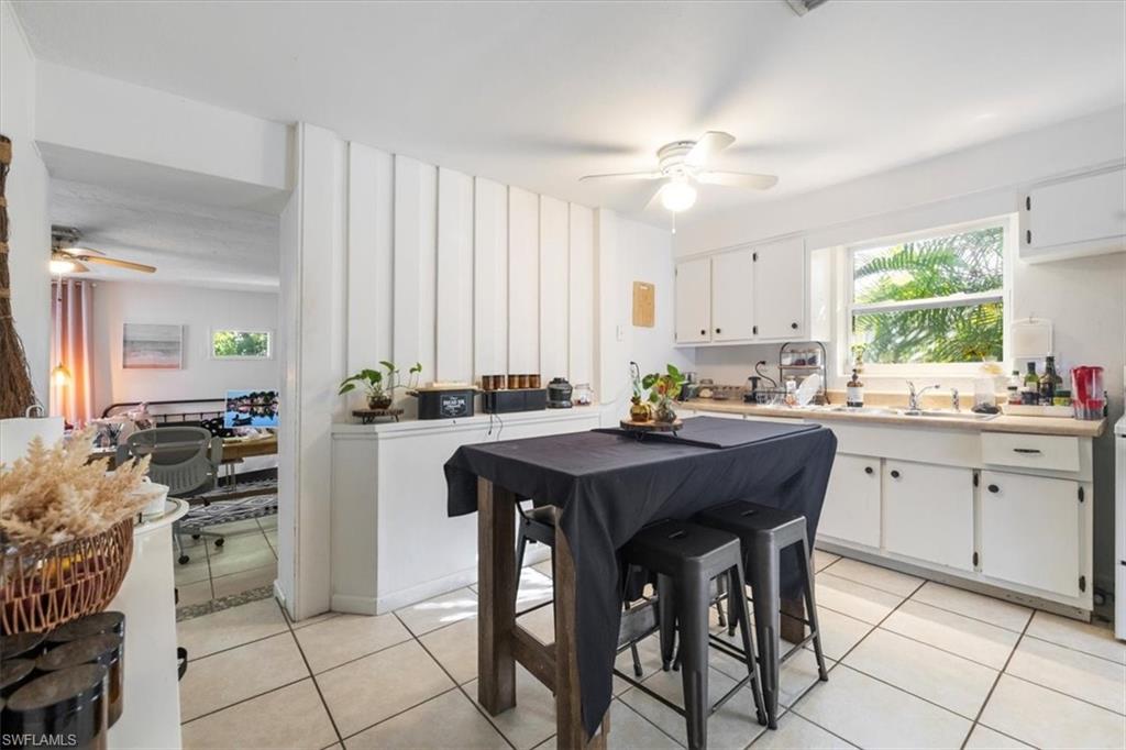 Kitchen with ceiling fan, light tile patterned floors, white cabinets, and light countertops