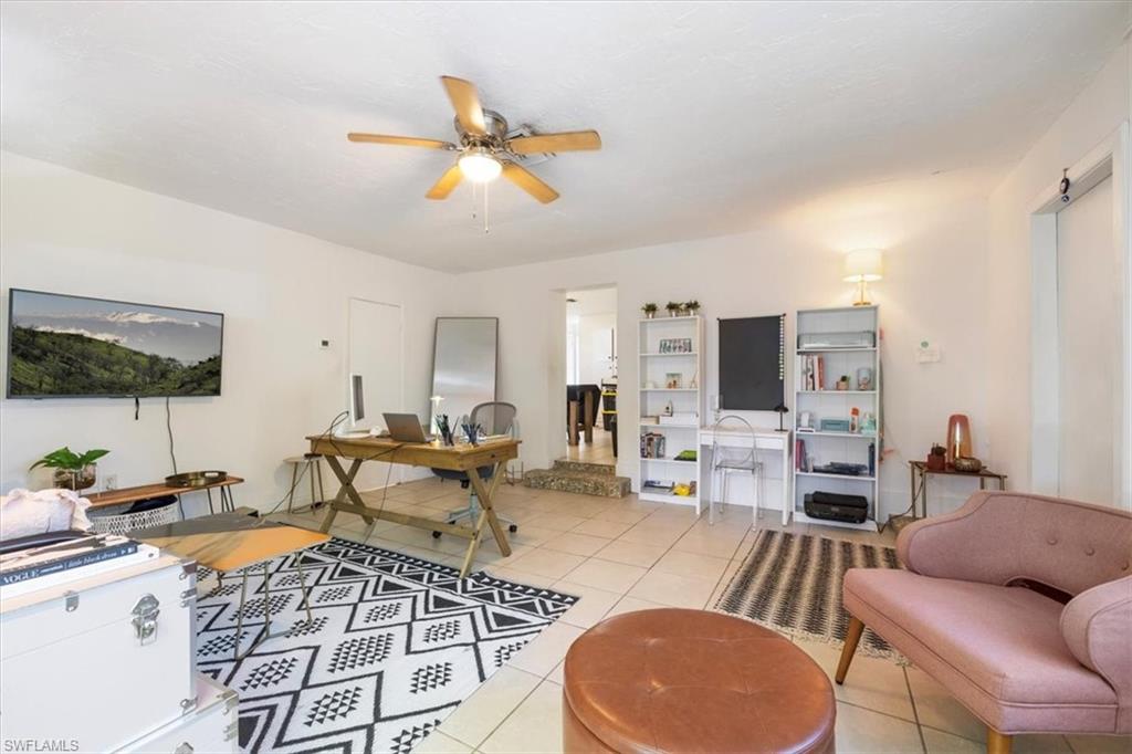Living area with light tile patterned floors, ceiling fan, and an office area
