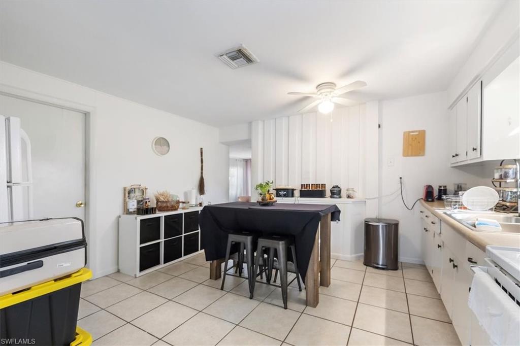 Kitchen featuring white cabinets, light tile patterned floors, light countertops, stove, and freestanding refrigerator