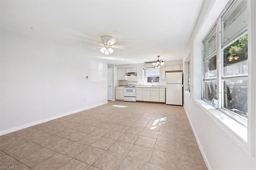Unfurnished living room featuring light tile patterned flooring, a chandelier, and a ceiling fan