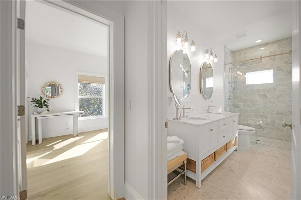 Bathroom with double vanity, marble tiled shower and floors