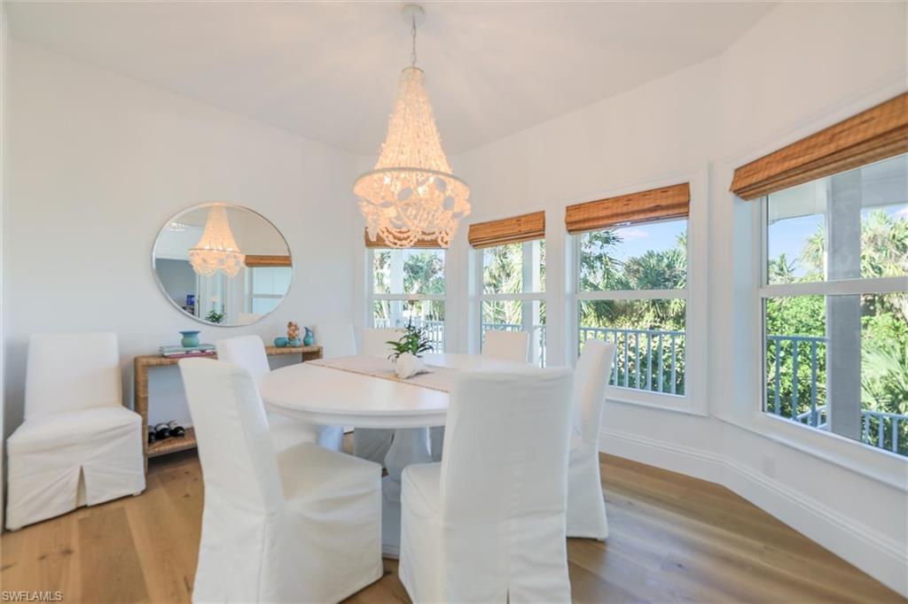Dining room featuring vaulted ceiling, wood-type flooring, plenty of natural light, and a notable chandelier