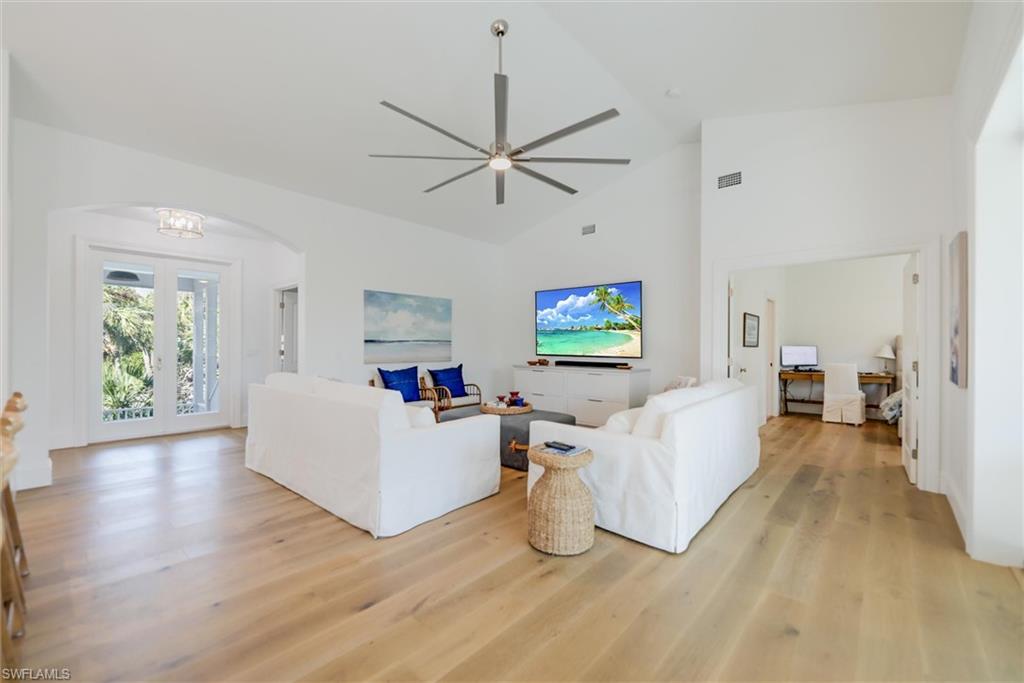 Living room with high vaulted ceiling, a chandelier, and light hardwood / wood-style floors