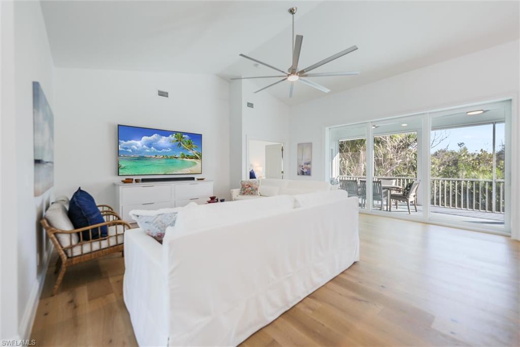 Living room with light hardwood / wood-style flooring, high vaulted ceiling, and ceiling fan