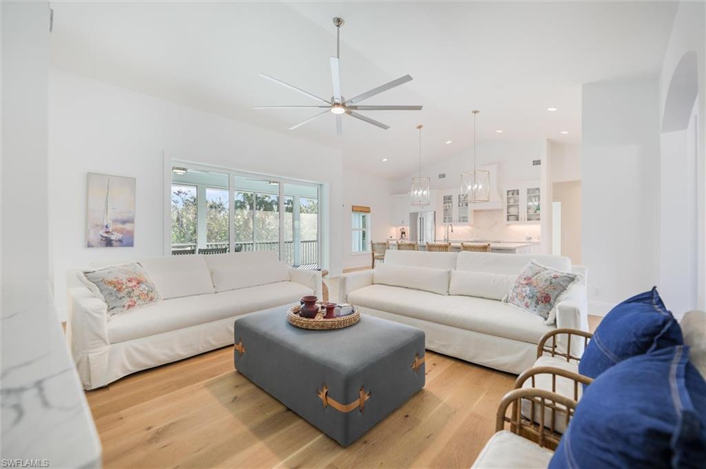 Living room featuring ceiling fan, high vaulted ceiling, and light hardwood / wood-style flooring