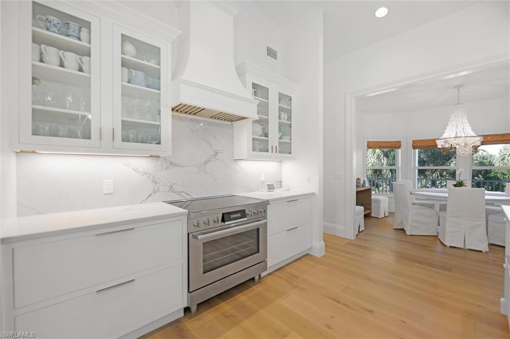 Kitchen with white cabinetry, pendant lighting, stainless steel range with electric cooktop, and premium range hood