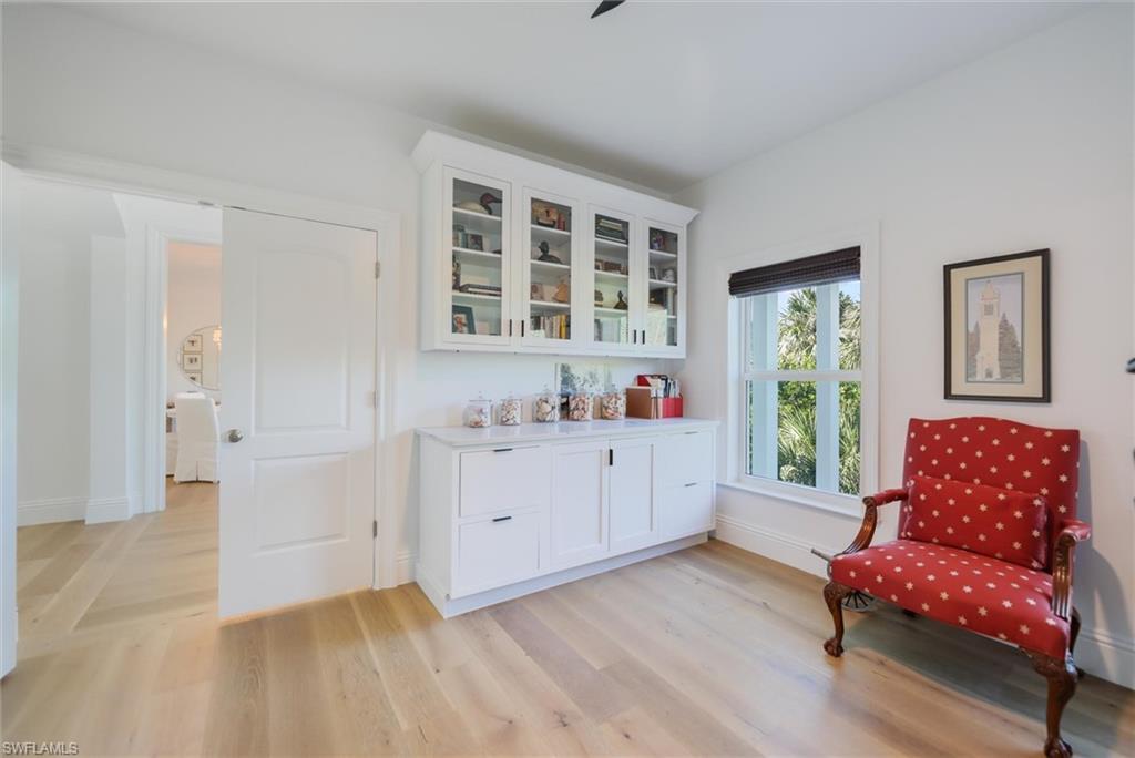 Bar with light hardwood / wood-style flooring and white cabinets