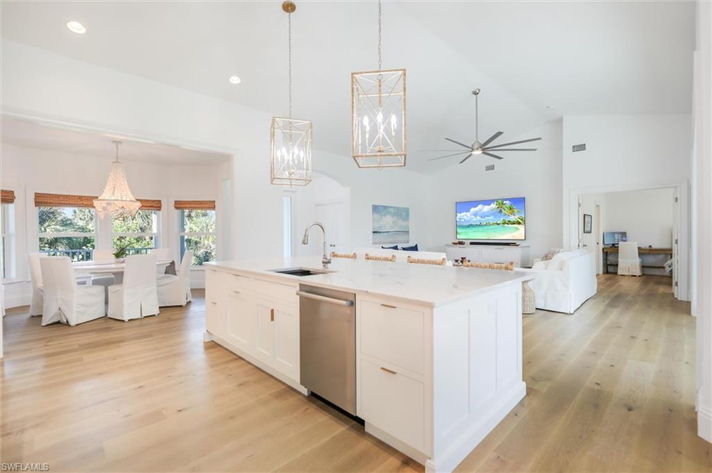 Kitchen featuring a center island with sink, white cabinetry, pendant lighting, and stainless steel dishwasher