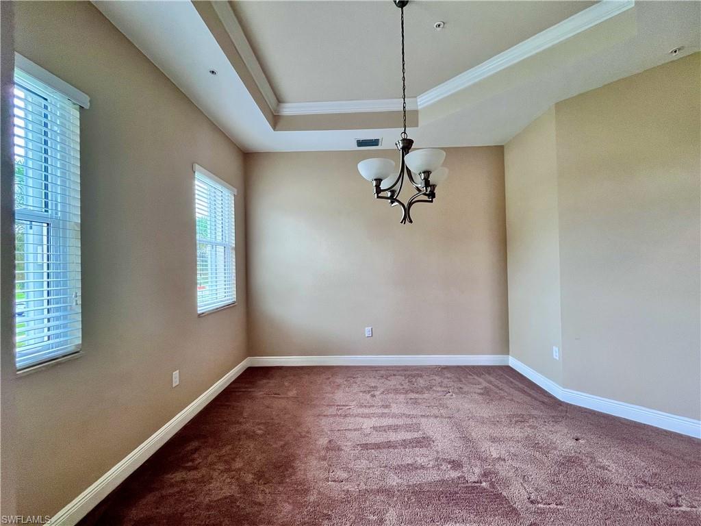 Formal Dining Room featuring carpet floors, a tray ceiling, ornamental molding, and a chandelier