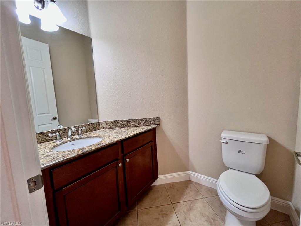 Half bath with a textured wall, vanity, and light tile patterned floors