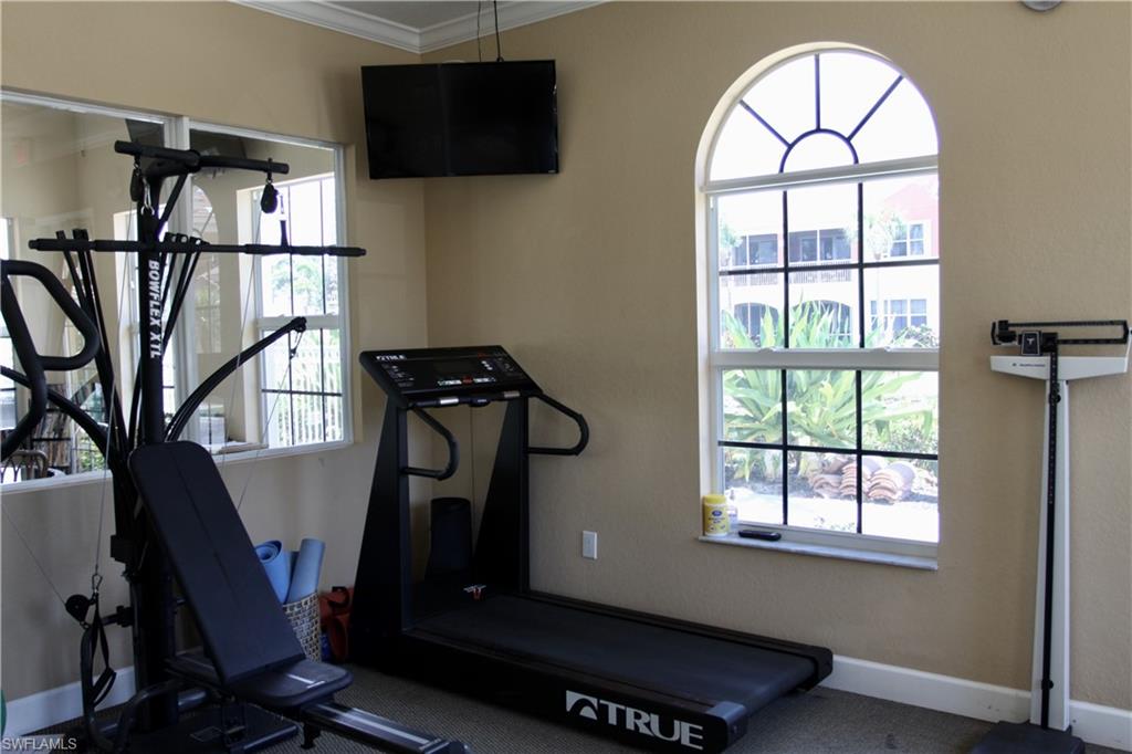 Exercise room featuring ornamental molding and baseboards