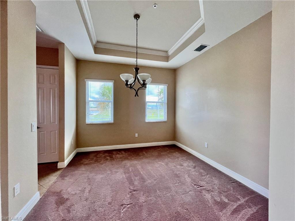 Formal dining area featuring carpet flooring, a chandelier, ornamental molding, and a tray ceiling
