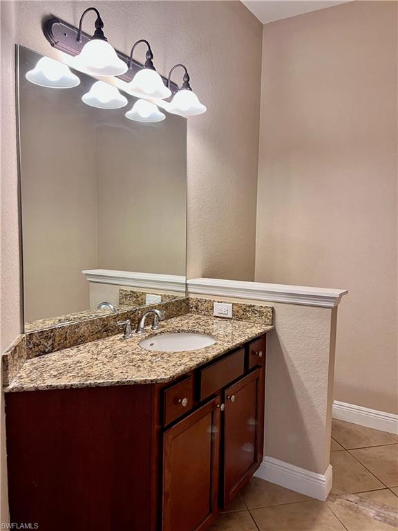 Bathroom featuring a textured wall, light tile patterned flooring, and vanity