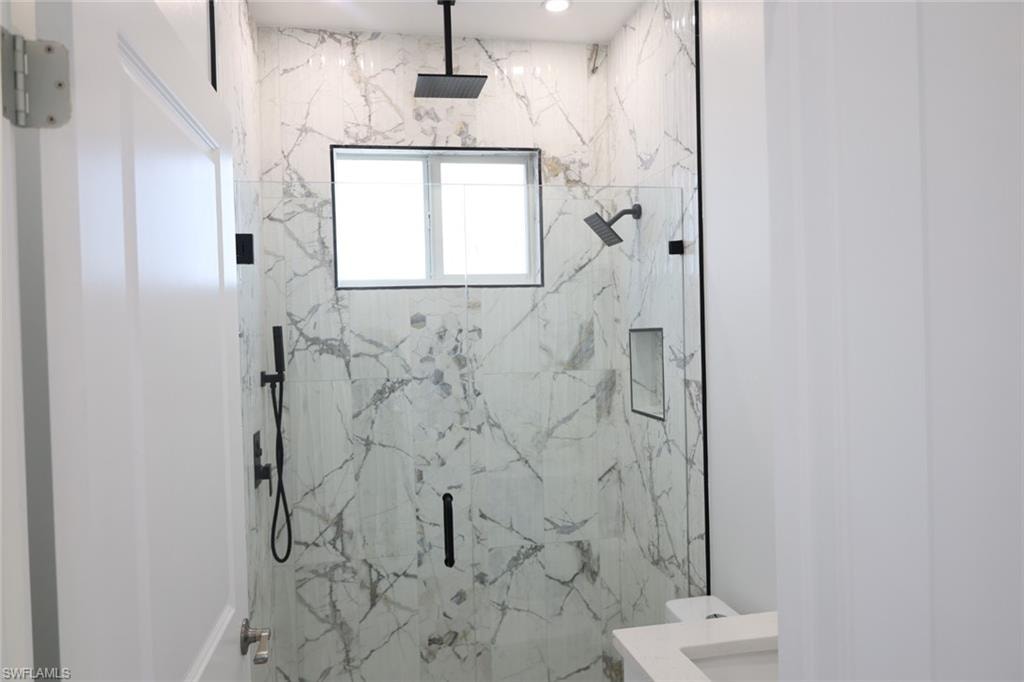 Bathroom with a marble finish shower and vanity