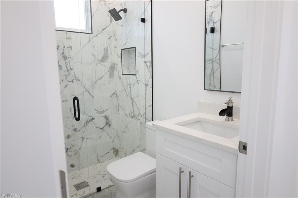 Full bath featuring a marble finish shower and vanity