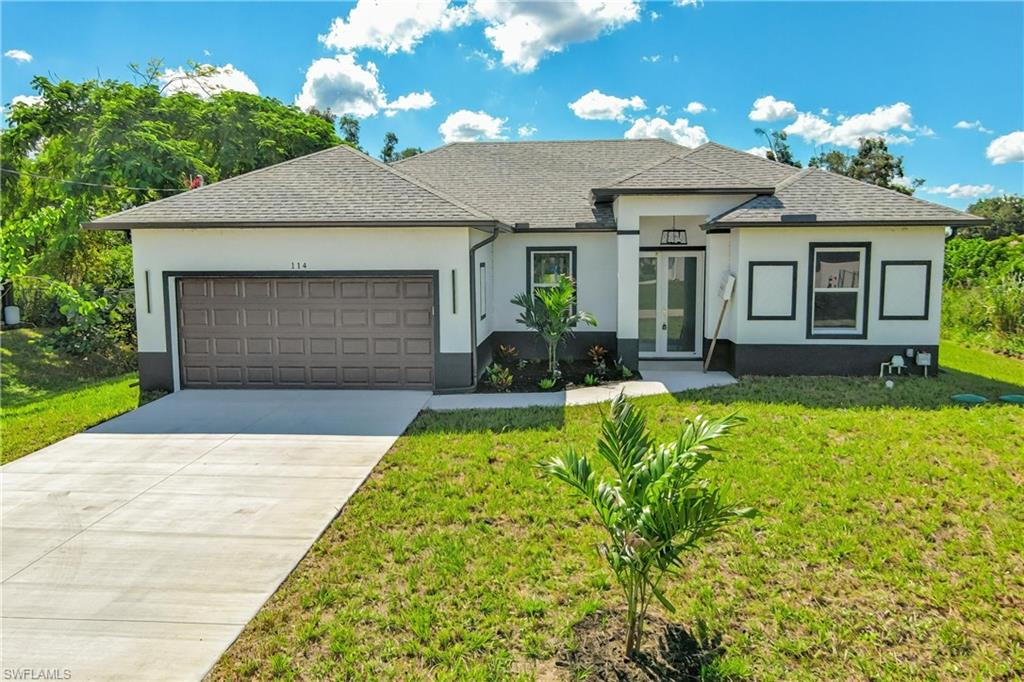 View of front of home with stucco siding, concrete driveway, and a shingled roof